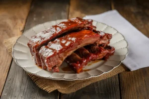 A white plate holds several glistening, sauced ribs.