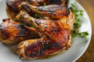 Several roasted chicken legs are arranged on a white plate, garnished with a sprig of parsley.