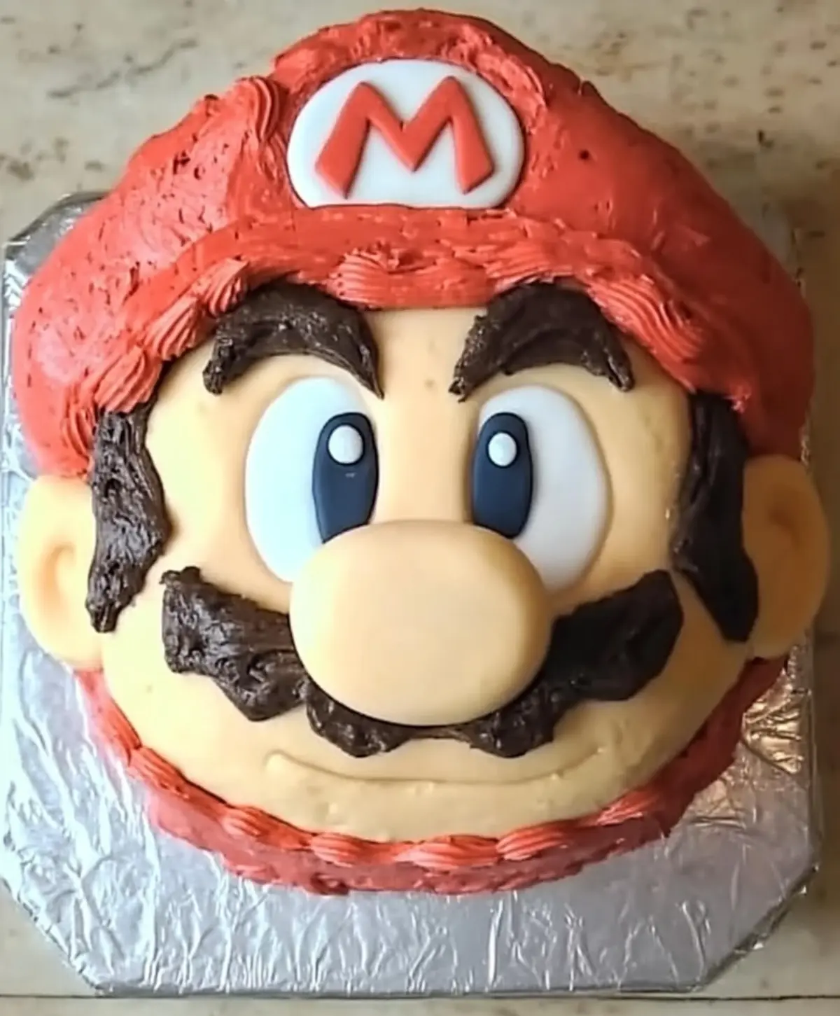 Cake with red and blue icing being piped for Mario’s hat design.