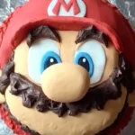 Realistic Mario birthday cake with detailed decorations on a wooden table